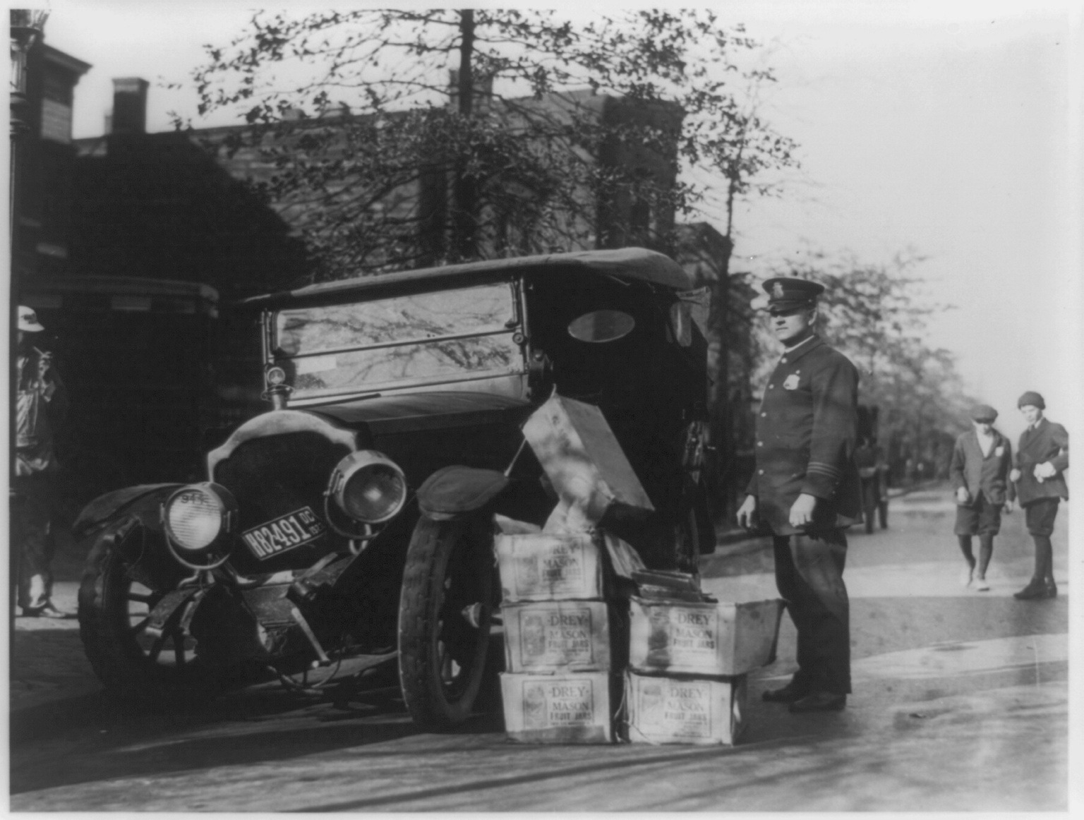 A policeman with wrecked automobile and confiscated moonshine, 1922
