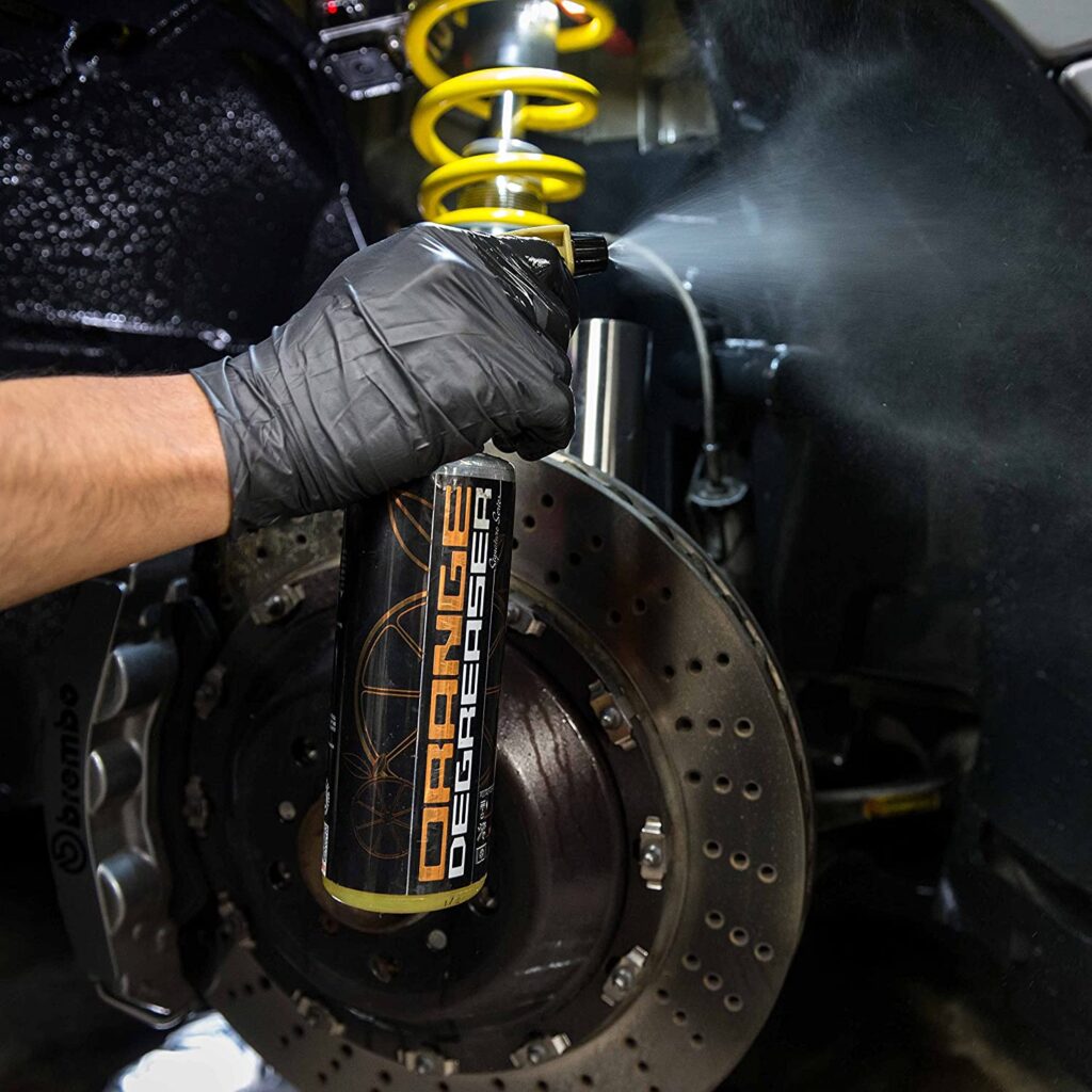 a person using a degreaser spray to clean his car