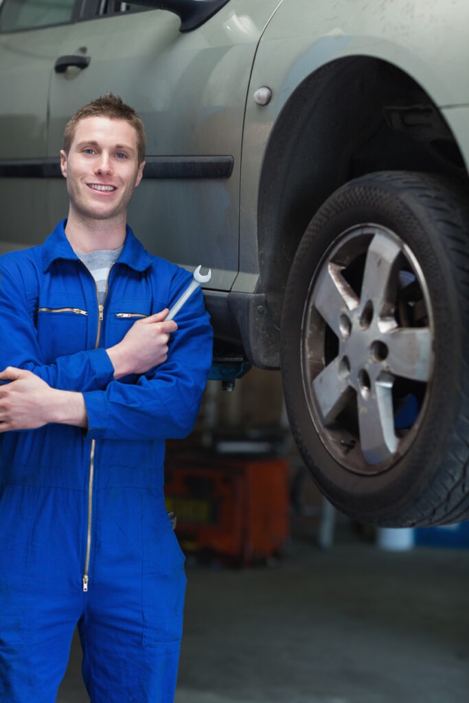Mechanic with hand tool standing by car