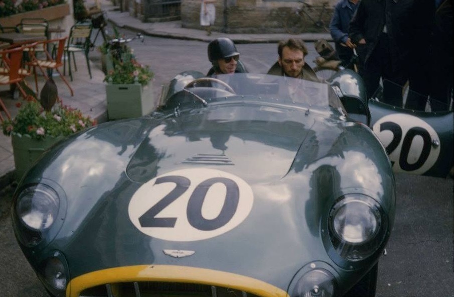Tony Brooks with mechanic, Eric Hind parked outside the 1957 Le Mans Aston Martin base, the Hotel de France, at the wheel of his DBR1 race car