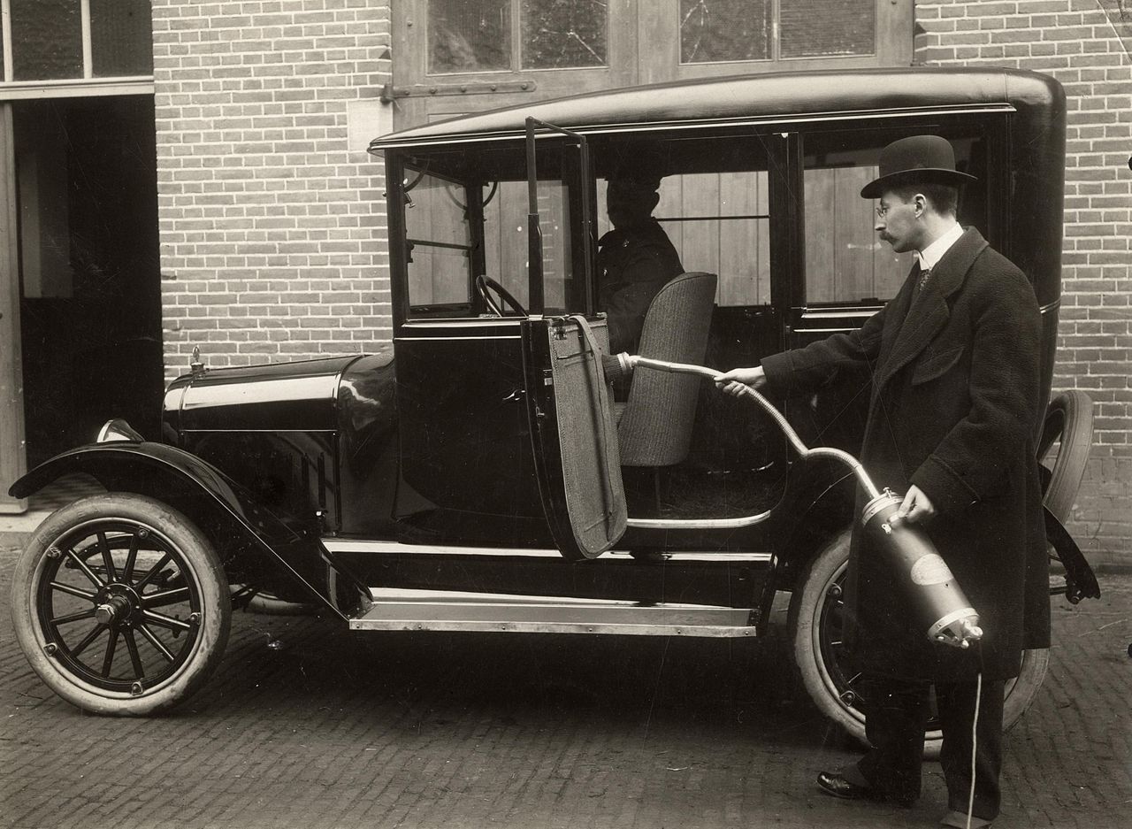 A man vacuuming the interior of an automobile in the Netherlands, 1916