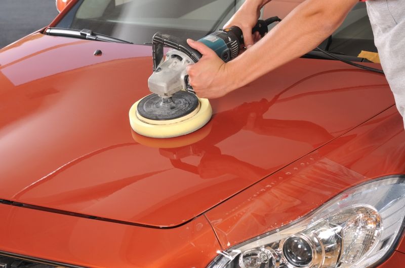 Close up of technician waxing car with polisher