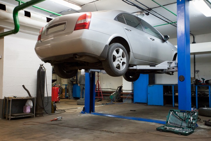  a car lifted by a two-post lift inside a garage