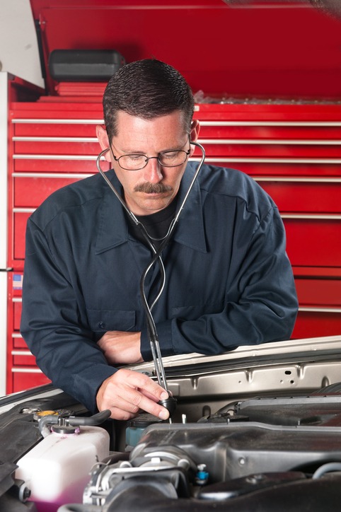 a man using an automotive stethoscope to check on a car’s engine