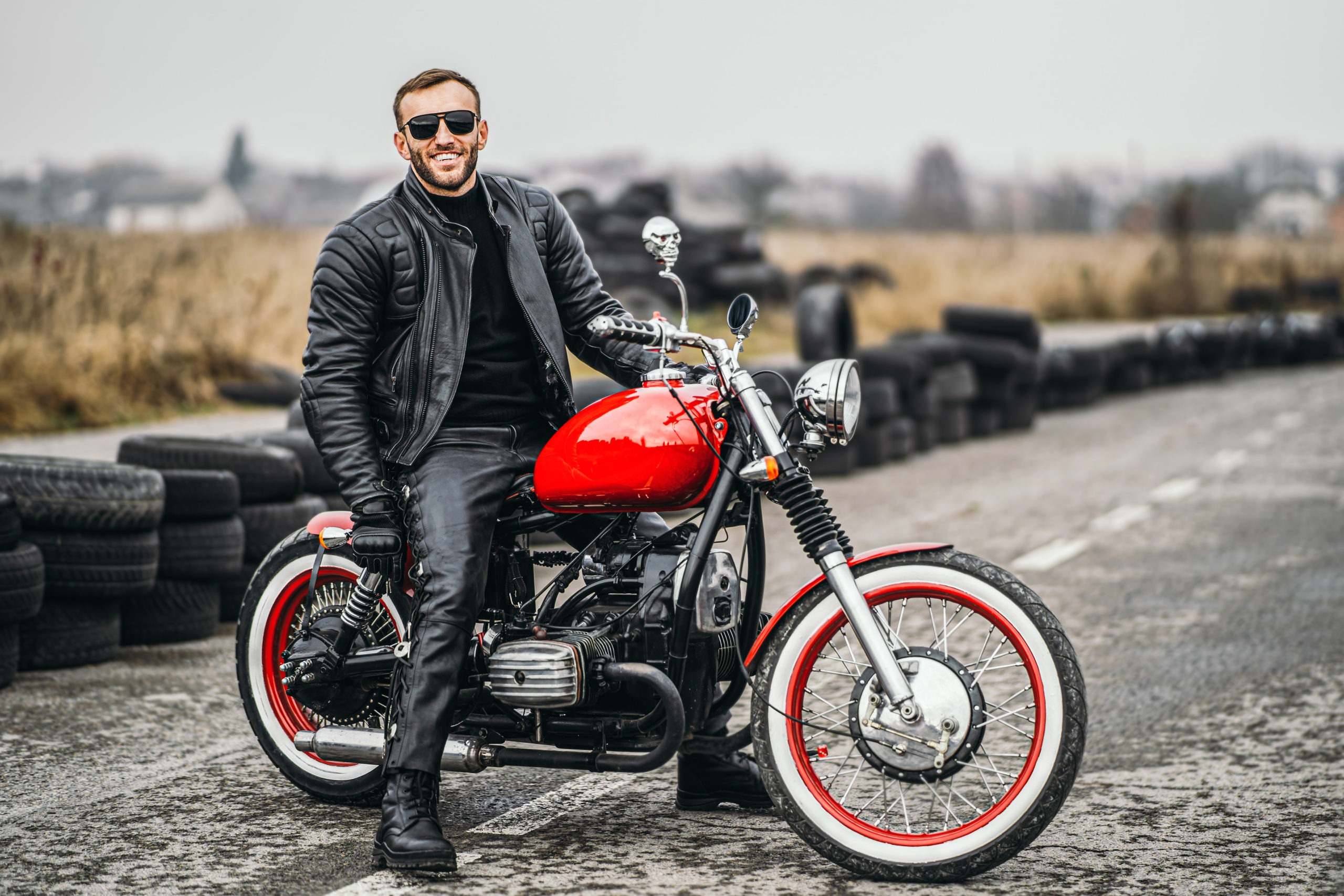 Red motorbike with rider. A man in a black leather jacket and pa