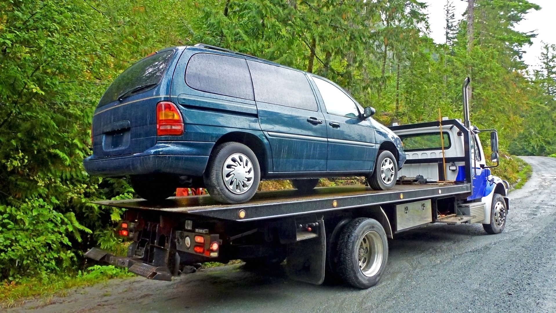Towing service - the blue tow truck with the loaded old damaged