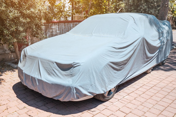 Car is covered with a cloth that protects from dust, UV solar radiation and other atmospheric influences in a tropical country with a hot climate