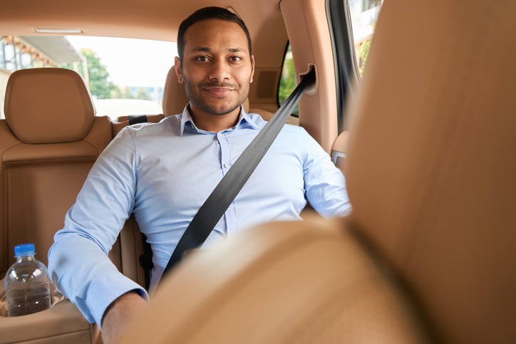 Calm pleased young man riding in luxury car