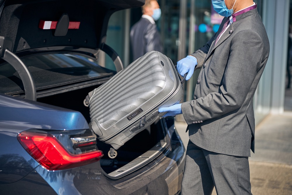 Chauffeur,In,Suit,Is,Packing,Luggage,Into,Car,Near,Airport