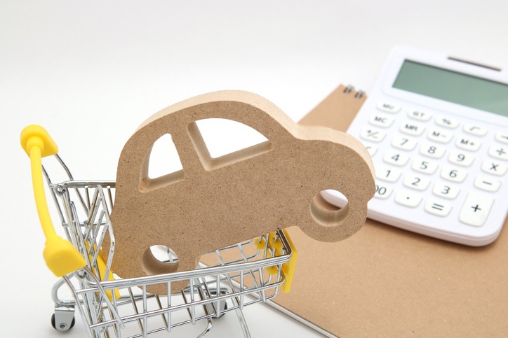 Miniature wooden car, shopping cart and calculator on white background. Concept of buying new car.