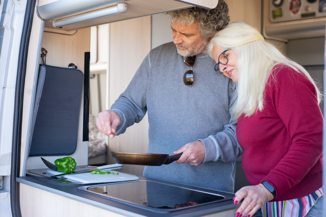 a couple cooking food using an RV’s kitchen
