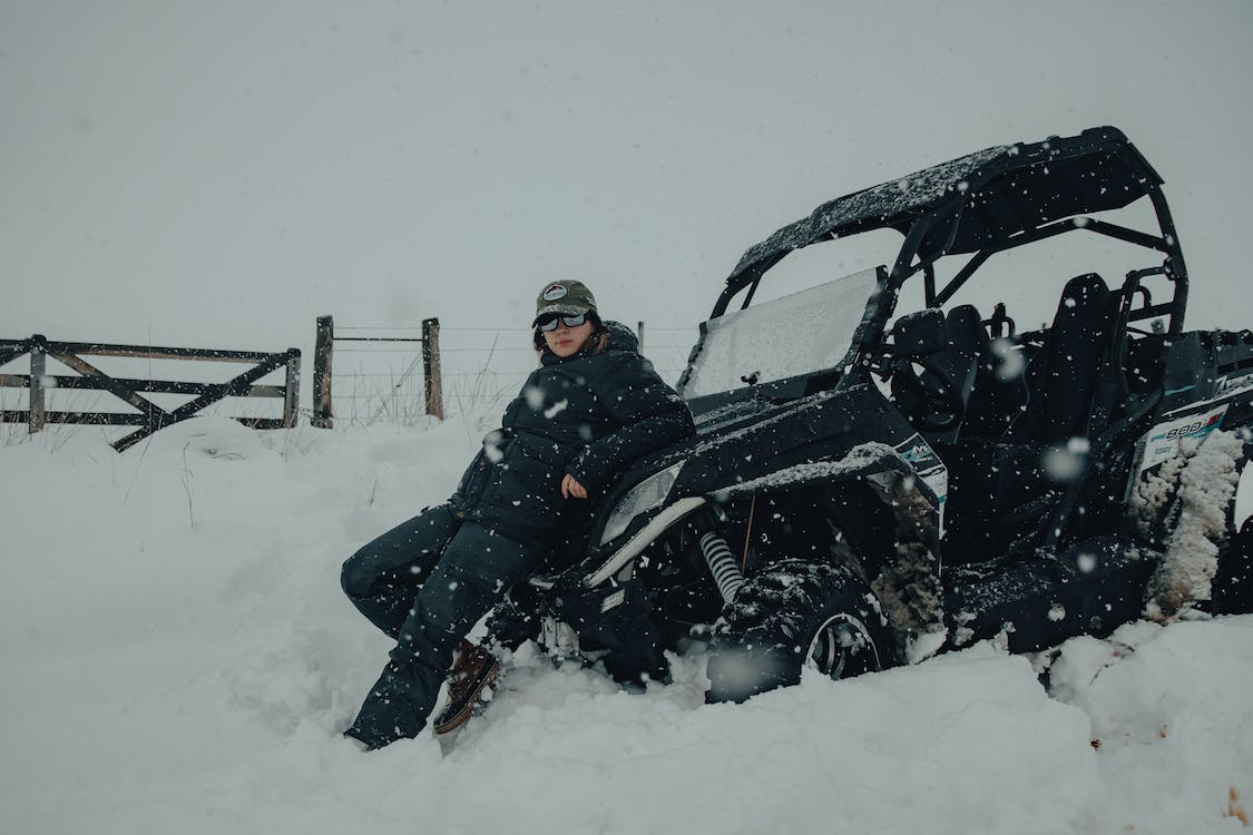 a person leaning on a utv in heavy snowfall