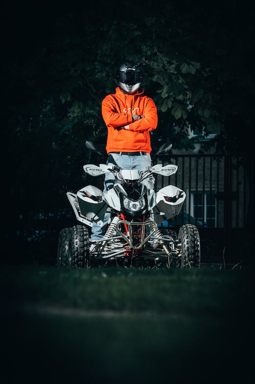 man in an orange jacket and helmet riding an ATV
