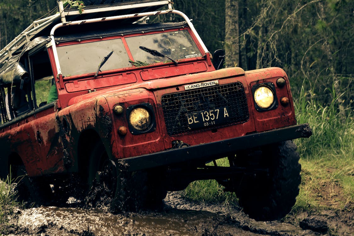 red car on a muddy road near trees