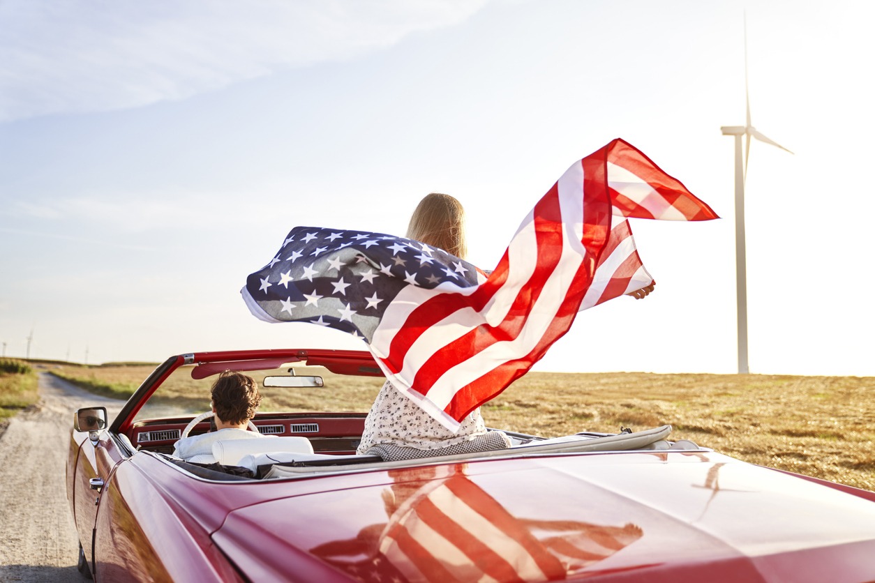 woman holding an American flag while riding a car