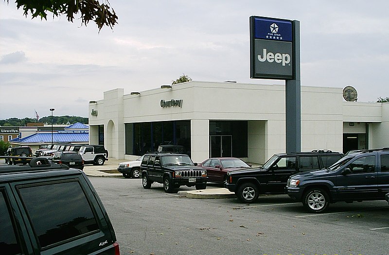 Typical car dealership (in this case a Jeep dealer) in the U.S. selling used cars outside, new cars in the showroom, as well as a vehicle entrance to the parts and service area in the back of the building