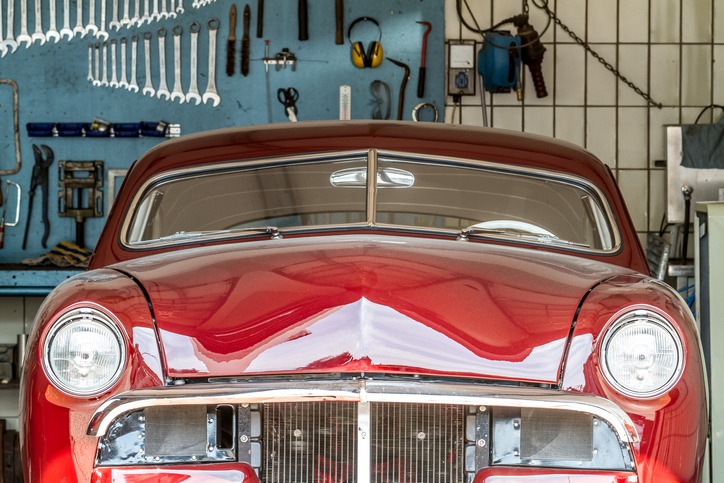 Red oldtimer in a car repair shop in process in front of a wall with screw-wreches