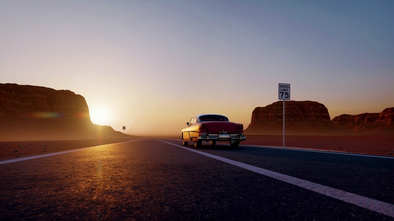 a classic car driving into the sunset