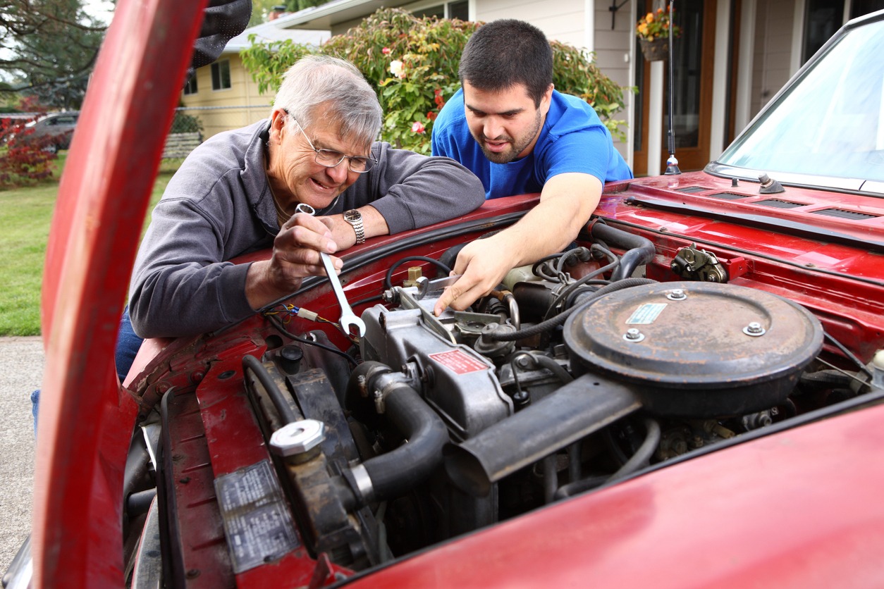 adult son and father working on a car engine