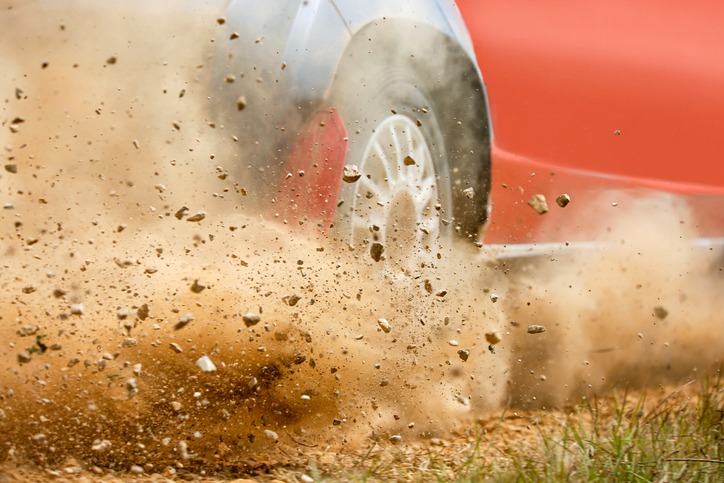 gravel splashing from a race car drift as the driver hits the brakes