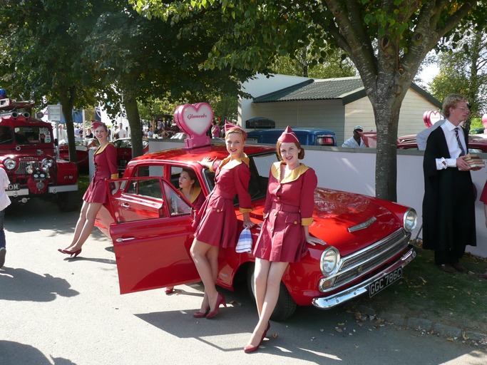 red retro car with women in period costumes at the Goodwood Revival