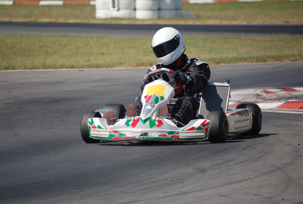 A go kart and driver racing round a track